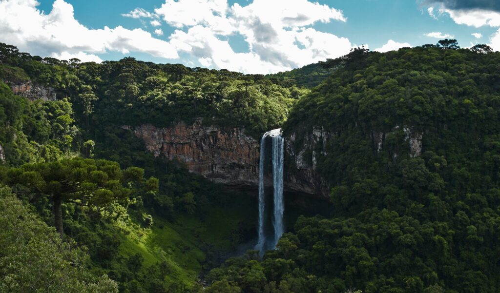 Explore the stunning waterfall amidst lush greenery in Gramado, Brazil.